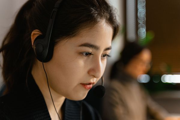 Nhân viên hỗ trợ châu Á đeo tai nghe làm việc tại văn phòng
